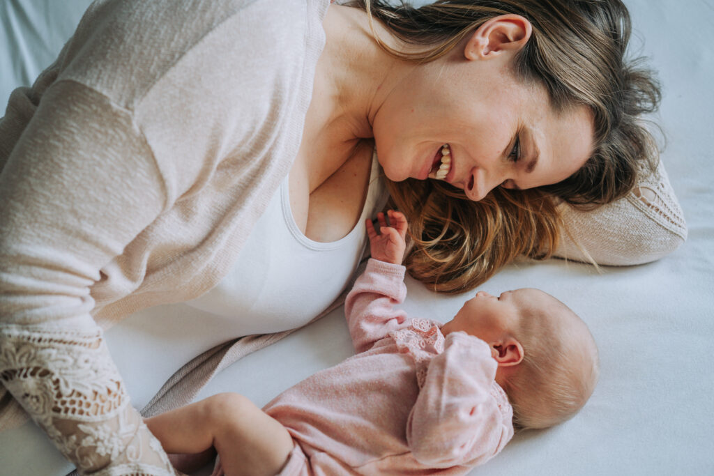 Eine Mama lacht ihr Baby bei einem Neugeborenenshooting in Bremen an.