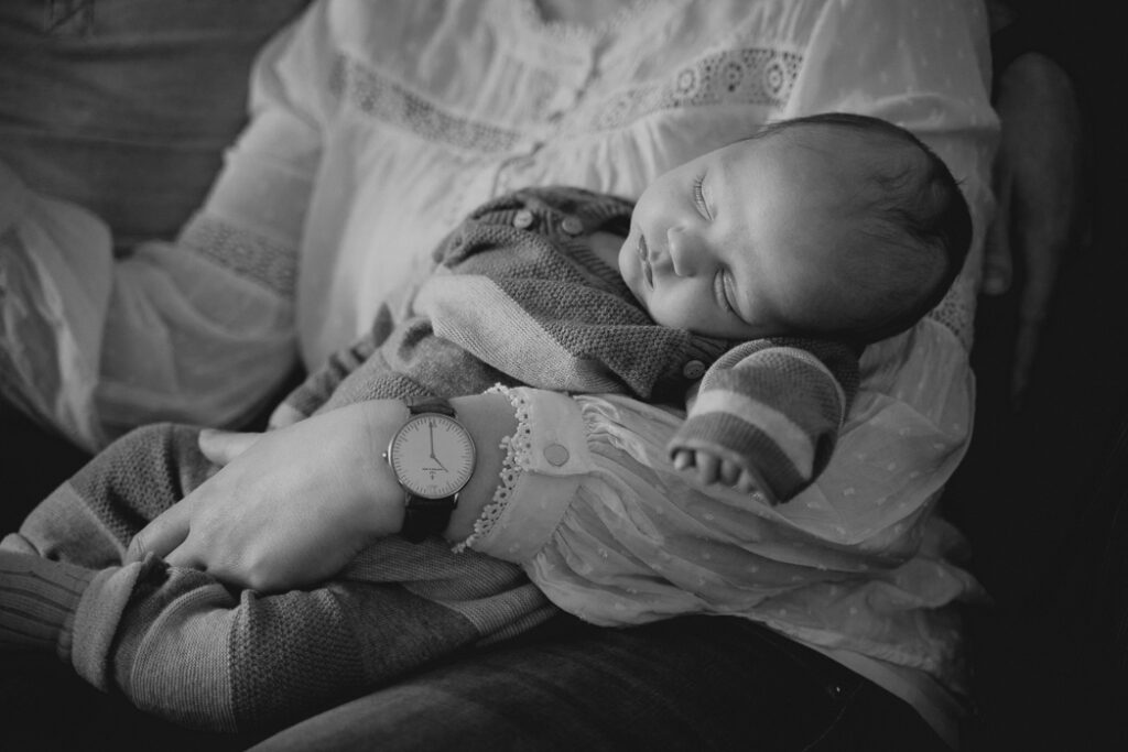 Ein neugeborenes Baby schläft auf dem Arm seiner Mutter.
