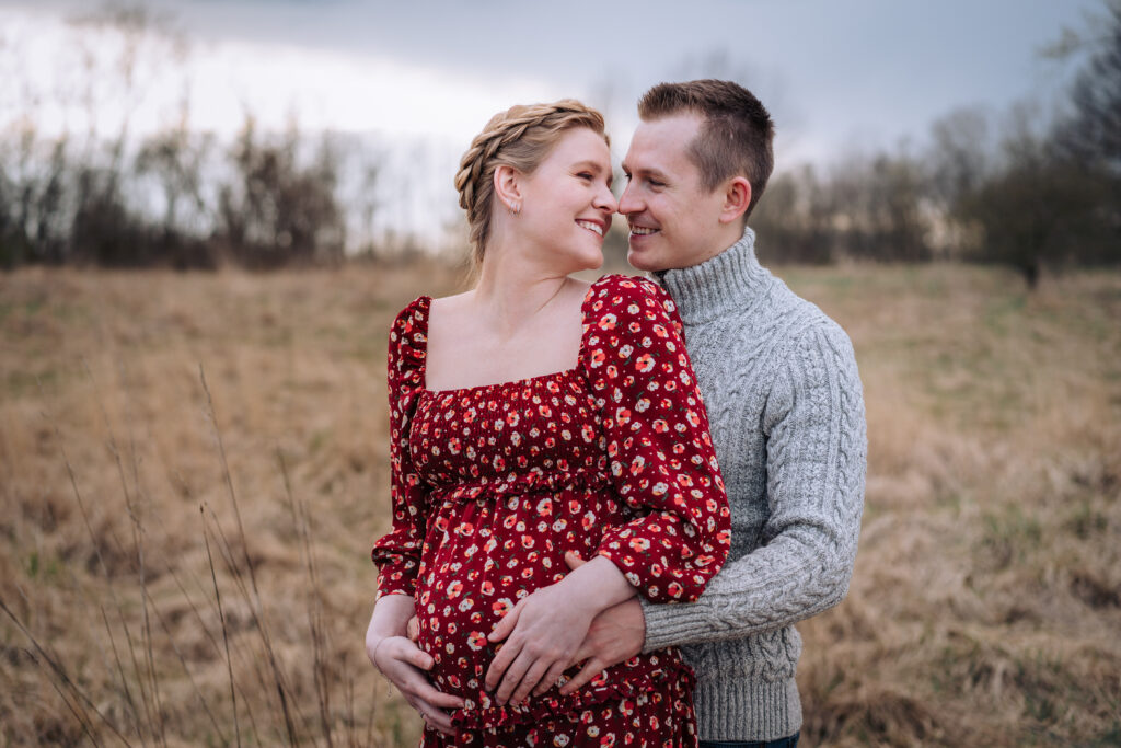 Ein Paar lächelt sich bei einem Schwangerschaftsshooting in Bremen an, währen der Mann die schwangere Frau umarmt.